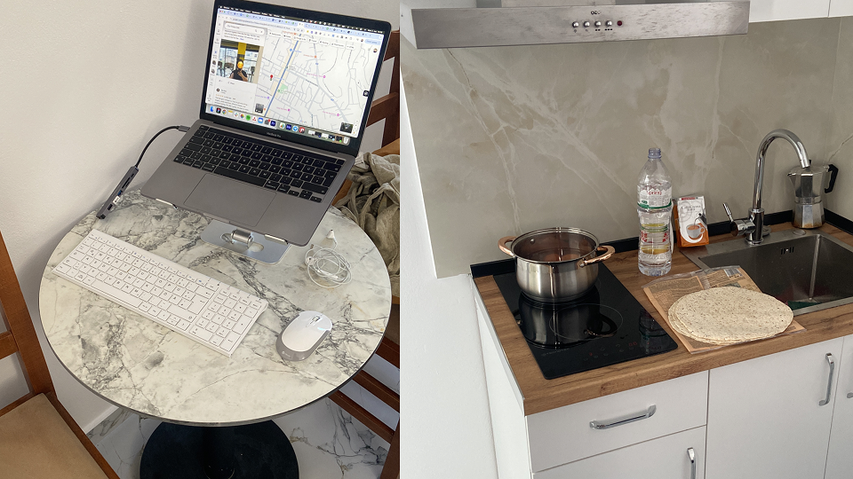 Workation Albanien: Laptop-Arbeitsplatz auf einem runden Marmortisch; daneben eine moderne weiße Küche mit Induktionskochfeld.