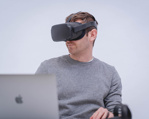 Über Mich: Jan Gemeinhardt mit einer VR-Brille und Macbook in der Forschung für Innovationstechnologien